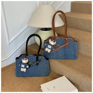 Detail der Jeans-Tasche mit Lederbesatz und süßem Teddybär-Anhänger auf Stufen
