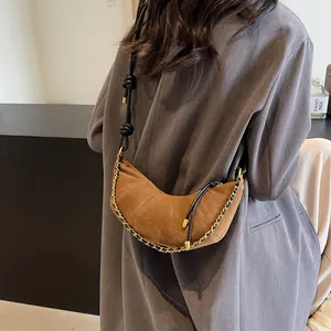 Brown frosted leather croissant bag with chain detail worn by a model in a grey blazer