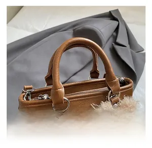 Detail of caramel leather bucket bag with silver hardware and plush puppy pendant accessory