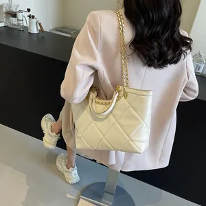 Chic quilted tote bag with gold chain straps and leather handles on a female model