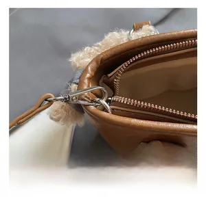 Detailed close-up of durable metal hook and shearling trim on brown bucket bag