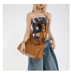 Dettaglio borsa tote in pelle lucida caramello con fibbia metallica vintage e manici