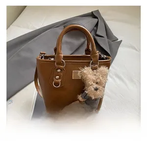 Brown faux leather bucket bag detail with cute bear charm and adjustable shoulder strap