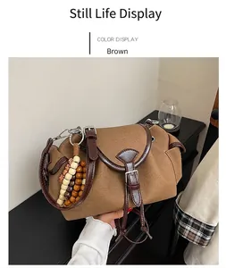 Close-up of vintage brown canvas handbag with leather trim and beaded pendant detail