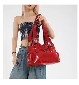Dettaglio macro della borsa tote rossa lucida con croce in metallo e fibbie decorative
