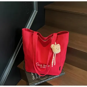 Detailed close-up of a stylish red canvas tote bag with cute bear charm on wooden stairs