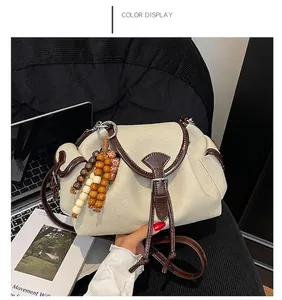 Detail of vintage canvas shoulder bag with brown leather trim and beaded ornament