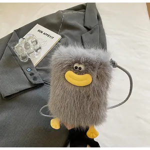 Détail du sac en peluche gris avec bouche de saucisse jaune et pieds sur tissu blanc