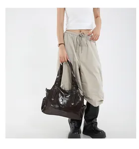 Borsa tote in pelle lucida marrone scuro con croce indossata da modella fashion