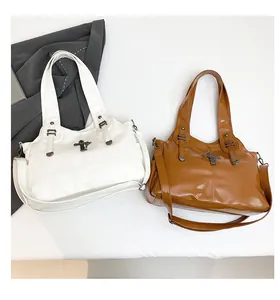 Dettaglio di borse tote in pelle PU bianca e marrone con croce metallica vintage