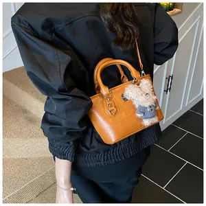 Detail of yellow bucket bag with glossy synthetic leather and plush bunny charm