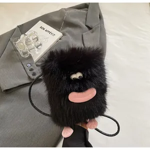Gros plan d'un sac en peluche noir avec lèvres roses posé sur une veste grise