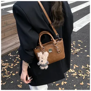 Detailed close-up of brown vintage leather bucket bag with cute plush bear pendant accessory