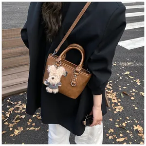Detailed macro view of brown faux leather texture and cute plush dog charm on bucket bag