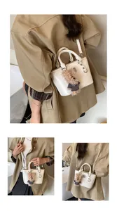 Detail of cream bucket bag showing textured synthetic leather and a cute teddy bear charm