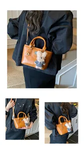 Detail view of ginger PU leather bucket bag with cute teddy bear charm and metal buckle