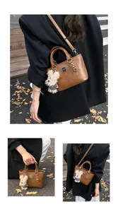 Detailed view of brown leather bucket bag with silver logo and cute puppy plush charm