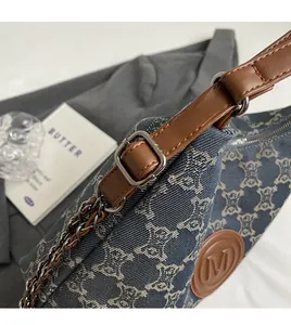 Detail of adjustable brown leather strap and metal buckle on monogram denim tote bag