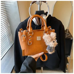Detail of a brown bucket bag featuring a textured finish and cute plush dog pendant