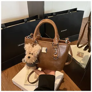 Detailed close-up of brown textured leather bucket bag with cute plush puppy charm