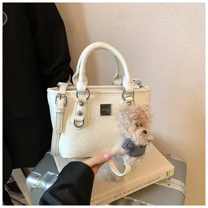 Detail of off-white bucket bag with lychee texture and cute plush dog pendant