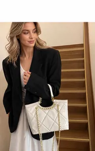 Detail of off-white quilted tote bag with gold chain strap on a professional model