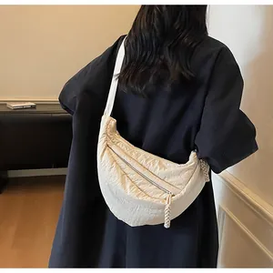 Detail of quilted beige crescent crossbody bag with wide strap and textured fabric finish