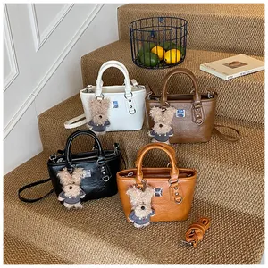 Detail view of four textured bucket bags in white, brown, and black with rabbit charms