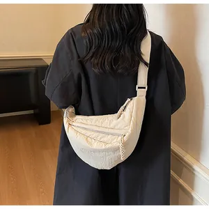 Detailed view of beige nylon dumpling crossbody bag with woven zipper and wide strap