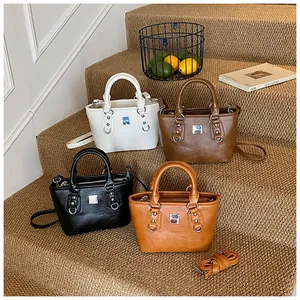 Detail view of stylish small bucket bags in white, dark brown, black, and caramel colors
