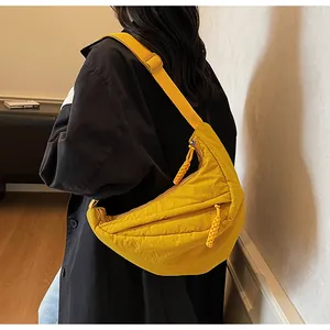 Detail of yellow nylon crescent bag featuring a woven rope zipper and adjustable strap