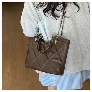 Close-up of deep brown quilted tote bag showing leather texture and golden chain strap
