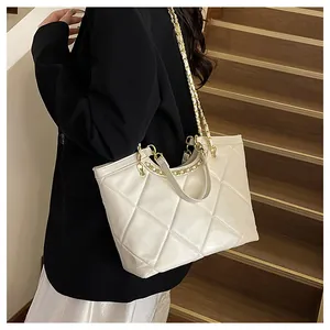 Close-up of cream quilted tote bag with gold chain strap on a wooden staircase