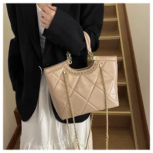 Close-up of beige quilted tote bag with golden chain strap and rhombus texture detail