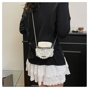 Detailansicht einer weißen gesteppten Mini-Tasche mit Perlengriff und Strass-Akzenten