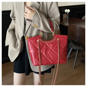 Detail view of the red quilted tote bag with gold chain strap and luxury texture