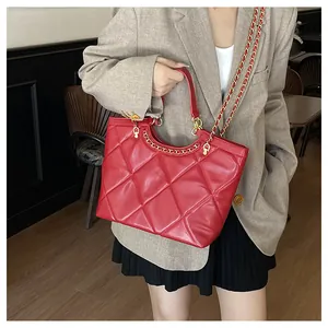 Detail of red quilted tote bag with golden metal chain strap and luxury leather texture