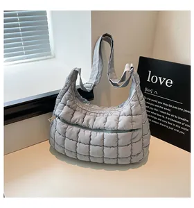 Detailed close-up of quilted puffy shoulder bag with front zipper and adjustable strap