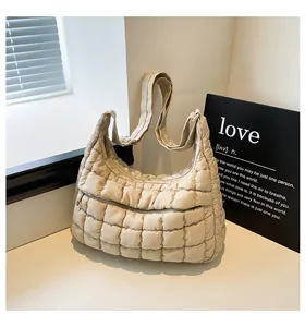 Detail of beige quilted hobo bag with grid pattern and front zipper pocket close-up
