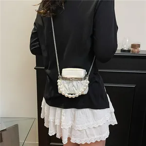 Elegante weiße Stepptasche mit Perlengriff und silberner Kette, getragen von einem Modell