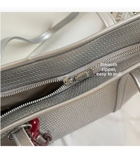 Detail of silver tote bag showing smooth metal zipper and woven texture craftsmanship