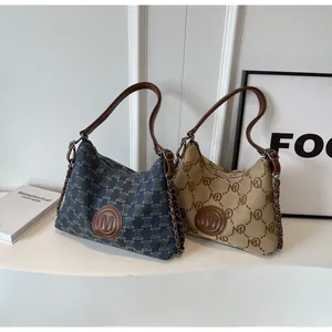 Detail of canvas tote bags with leather logo patch and metal chain shoulder straps