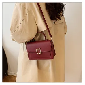 Détail du sac bordeaux en cuir texturé avec boucle dorée en U et fine bandoulière