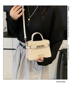 Detailed close-up of the elegant metal twist lock and embossed logo on the cream handbag
