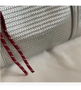 Macro detail of silver woven tote bag fabric texture with a decorative red and white cord