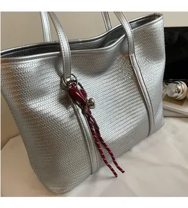 Detail of silver woven texture tote bag with red heart charm and tassel ornament