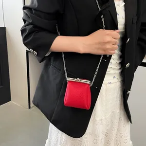 Mini red lychee leather lipstick bag with silver clasp and metal chain strap worn by model