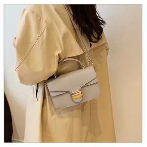 Détail d'un sac à main gris en cuir grainé porté avec un trench pour un look chic