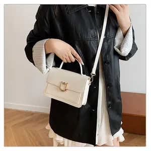 Détail du sac carré beige avec finition texturée et fermoir en forme de U doré élégant