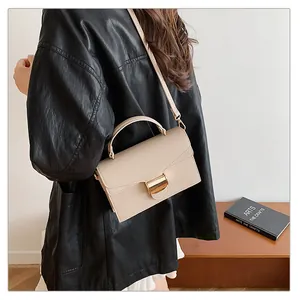 Détail du sac beige texture litchi avec boucle en métal doré et poignée main